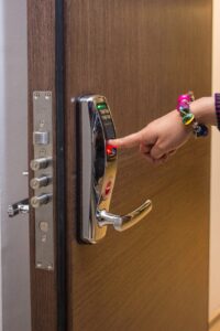 A hand using fingerprint access on a digital security door lock, enhancing safety