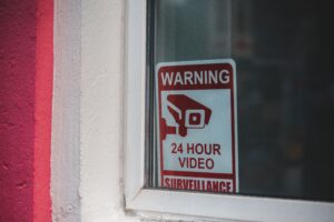 Close-up of a red warning sign for 24-hour video surveillance on a window.