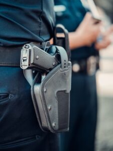 Detailed view of a police officer's gun holstered on the belt with blurred background.