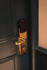Access control through Elegant brass handle and lock on a wooden door with soft lighting.