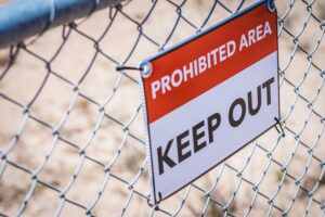 Security sign on fence: "Prohibited Area - Keep Out"